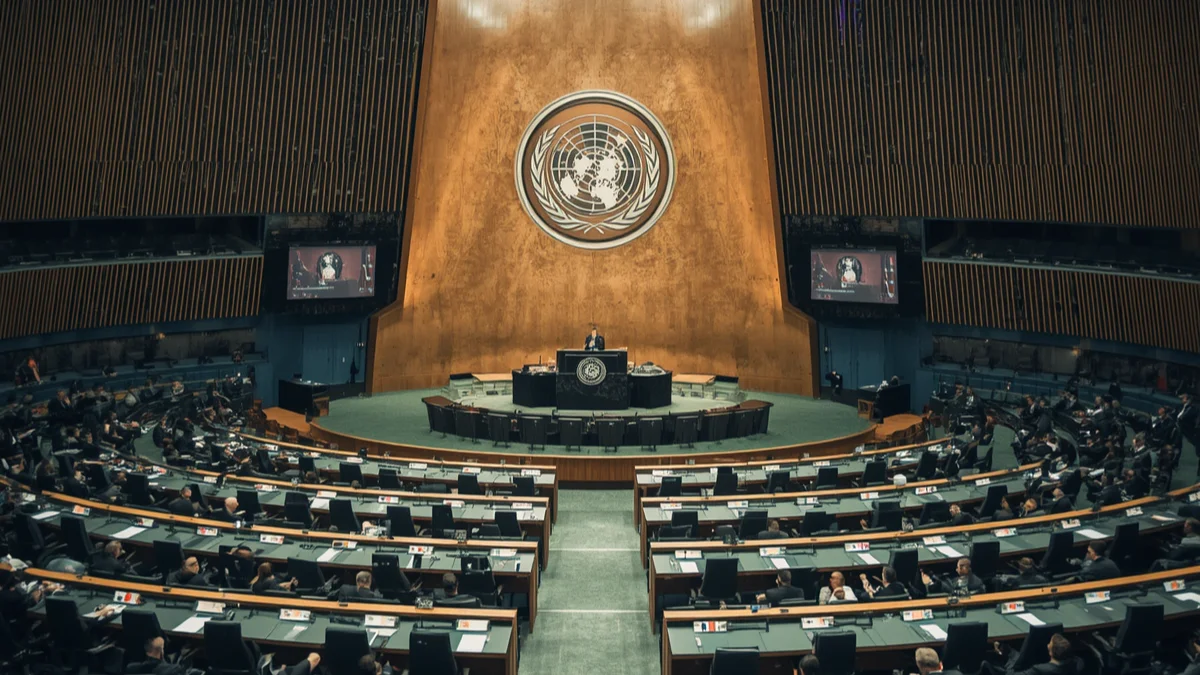 International aviation safety conference hall with delegates and national flag placards, representing the 2026 FAA–EASA International Aviation Safety Conference cooperation declaration`